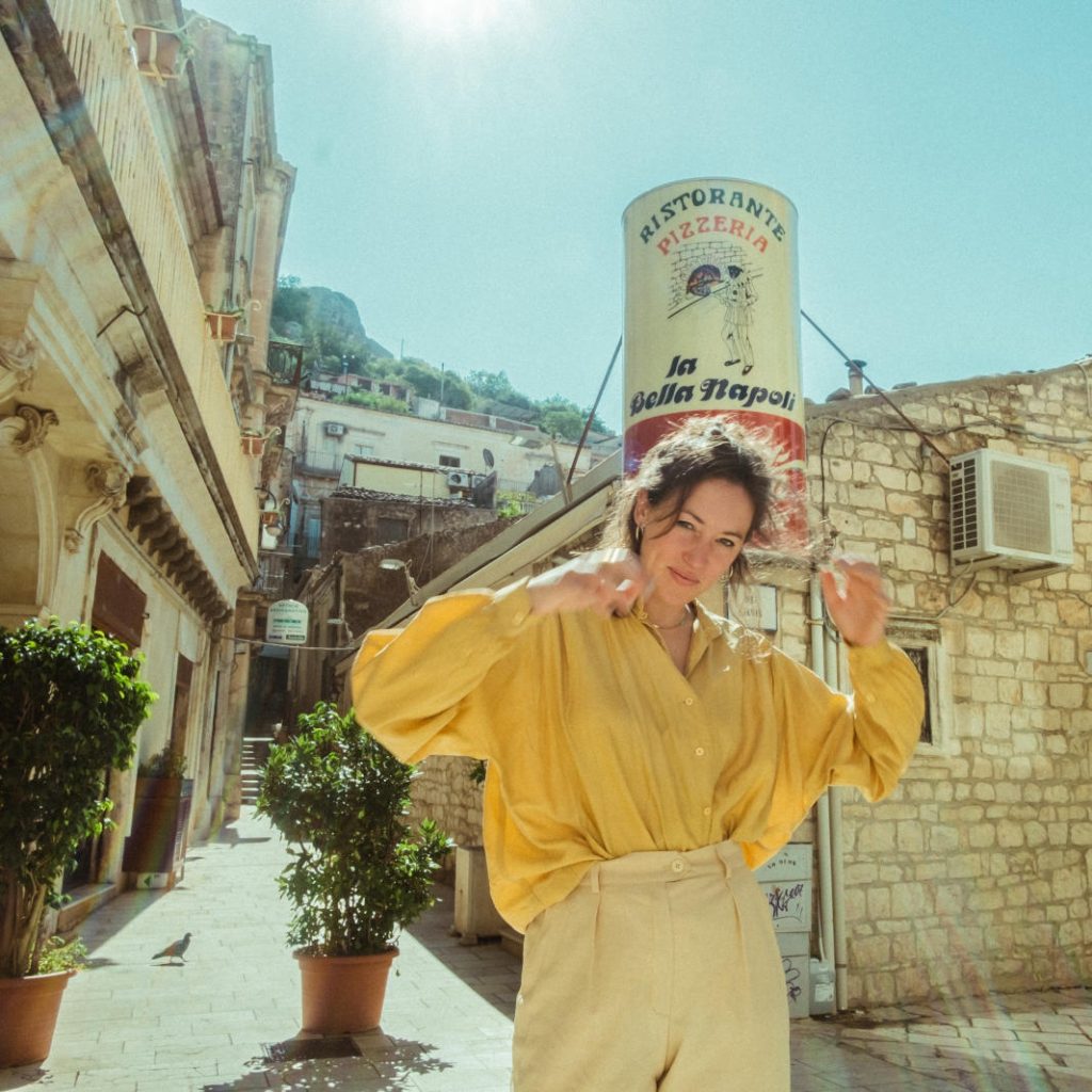Johanna Amelie in einer gelben Bluse vor einer italienischen Pizzeria