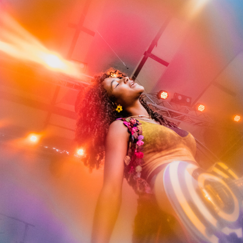 Uche Yara, singing and dancing in bright stage light
